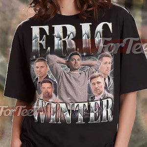 May include: Black unisex t-shirt featuring a graphic of Eric Winter with the name "ERIC WINTER" in a silver, metallic font. The shirt includes the text "For Tee" and "UNISEX SHIRT".