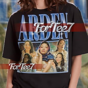 May include: Black unisex t-shirt featuring a graphic print of a collage of women's faces and the text "ARDEN For Tee7".