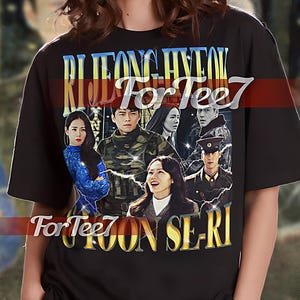 May include: Black unisex t-shirt with a graphic print of actors from the Korean drama "The K2". The text "RI JEONG HYUK For Tee7 For Tee7 JOON SE-RI" is printed on the shirt.