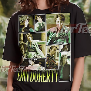 May include: Black unisex t-shirt featuring a collage of images and the name "ERIN DOHERTY" in yellow. The shirt has a crew neck and short sleeves. The text "UNISEX SHIRT" is at the top.