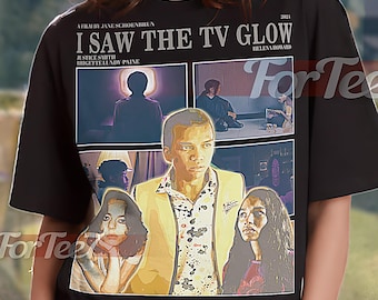 May include: Black unisex t-shirt featuring a movie poster design for "I Saw the TV Glow." The graphic includes a collage of images and the film's title, director, and cast. The shirt is labeled "UNISEX SHIRT."