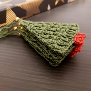 May include: A green crocheted Christmas tree ornament with a red crocheted star on top.