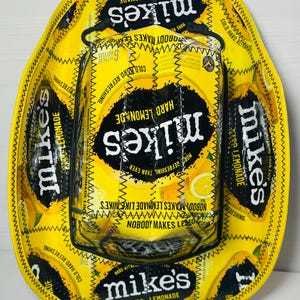 Puede incluir: Un sombrero de vaquero amarillo y negro con el tema de Mike's Hard Lemonade. El sombrero est&aacute; hecho de las latas de la bebida y presenta el logotipo y el texto de la marca. Un art&iacute;culo &uacute;nico y hecho a mano.