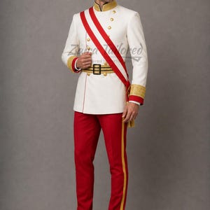 Puede incluir: Una chaqueta de estilo militar blanca con cuello y puños dorados, ribetes rojos y botones dorados, combinada con pantalones rojos con una franja lateral dorada. Una banda roja con ribete dorado y un cinturón dorado con hebilla negra.