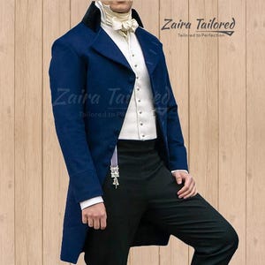 Op de afbeelding: Een blauw colbert met een wit vest en een zwarte broek. Het colbert heeft een zwarte fluwelen kraag en een witte strik. De tekst "Zaira Tailored" is zichtbaar op de afbeelding.