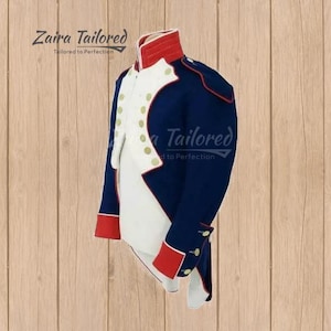 Peut inclure: Une veste de style militaire bleu fonc&eacute; avec un col montant rouge, des revers blancs et des poignets rouges. Le v&ecirc;tement est orn&eacute; de boutons dor&eacute;s sur le devant et les manches. Le texte Zaira Tailored Tailored to Perfection est visible.