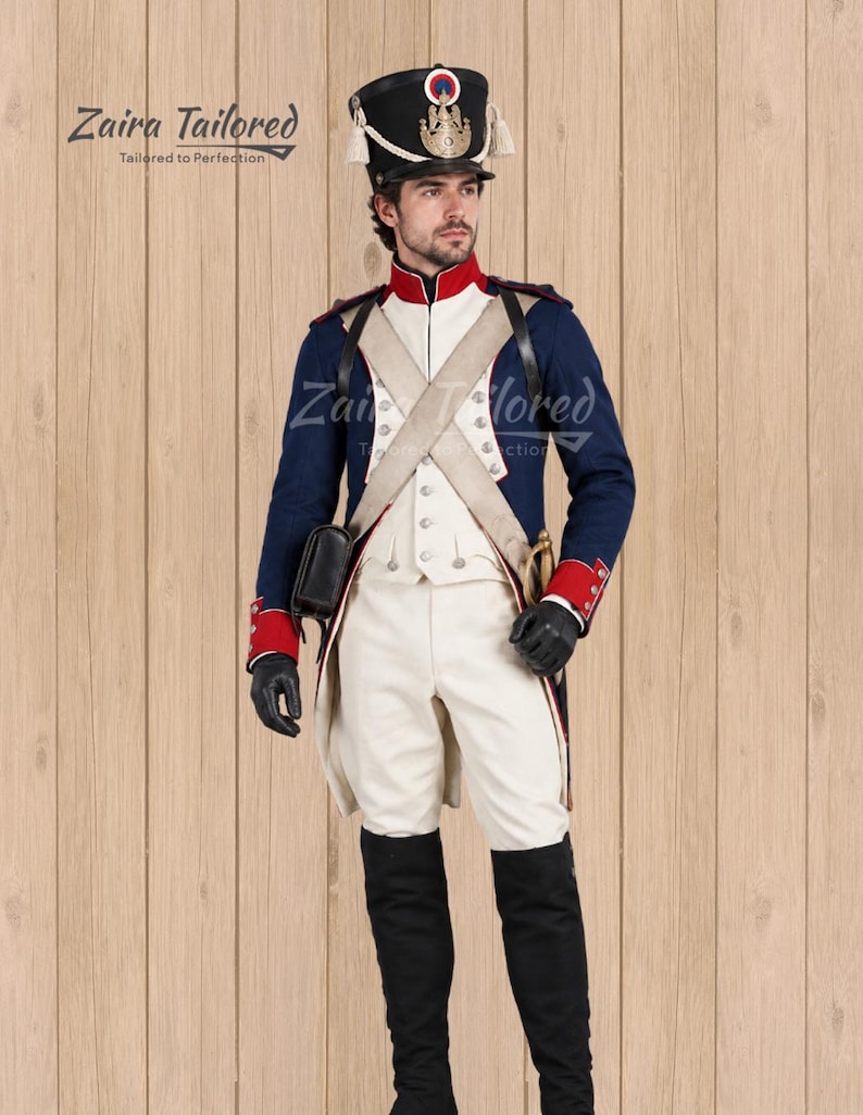 Peut inclure: Un uniforme militaire historique compos&eacute; d'une veste bleu marine &agrave; parements et col rouges, d'un pantalon blanc et d'un shako noir orn&eacute; d'un embl&egrave;me dor&eacute;. L'ensemble comprend des bandouli&egrave;res blanches, des gants noirs et des bottes hautes.
