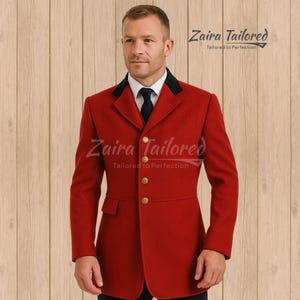 Puede incluir: Una blazer roja a medida con cuello verde oscuro y botones dorados. La blazer tiene un diseño clásico y un corte entallado. La marca "Zaira Tailored" es visible en la imagen.
