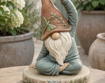 May include: A garden gnome figurine in a seated yoga pose with one arm raised. The gnome wears a terracotta-colored hat with a green dragonfly and vine relief, and a muted blue outfit. It sits on a circular base decorated with a butterfly and flowers.