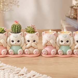 May include: Two sets of three cream-colored cat figurines on a pink base. The first set holds small green succulents, while the second set features lit tea light candles. Each cat has a different pose, covering its eyes, ears, or mouth.
