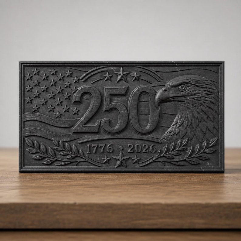 May include: A rectangular black plaque featuring a relief design of a bald eagle, the number 250, and the years 1776 and 2026. The design includes a stylized American flag with stars and stripes, framed by laurel branches and additional stars.