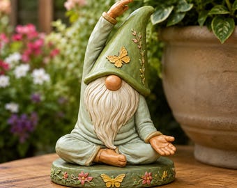 Peut inclure: Une figurine de nain de jardin en position de yoga assise avec un bras levé. Le nain porte une tenue vert sauge et un chapeau pointu assorti orné d'un papillon jaune. La base présente un motif floral et un dessin de papillon jaune.