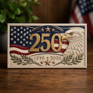 May include: A rectangular plaque featuring a carved American flag background with the gold numbers 250, a bald eagle head on the right, and the years 1776 and 2026 below. The design includes gold stars and green laurel branches in a relief style.