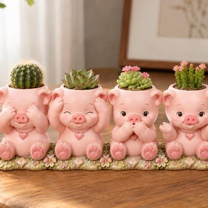 May include: A set of four light pink pig-shaped planters arranged in a row on a floral base. Each pig features a heart-shaped pendant and a different pose, holding a small green cactus or succulent plant in its open top section.