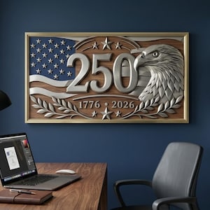 A wooden wall art piece featuring the American flag, an eagle, and the number 250. The artwork is framed in gold and includes the years 1776 and 2026. The piece is displayed on a dark blue wall.