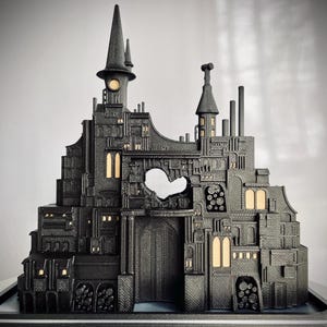May include: A black 3D printed model of a gothic-style building with a heart-shaped opening in the center. The building has a tall tower with a pointed roof and many windows. The model is detailed and intricate, with many small features.