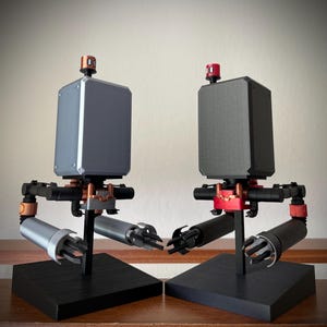 May include: Two robot figures with articulated arms and legs, one is gray and the other is black, both have red accents and are posed facing each other.