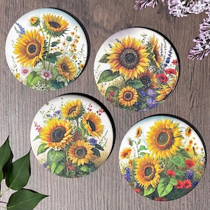 May include: Set of four round coasters featuring colorful sunflower designs with green leaves and other floral accents. The coasters are made of a durable material and are perfect for protecting surfaces from scratches and spills.