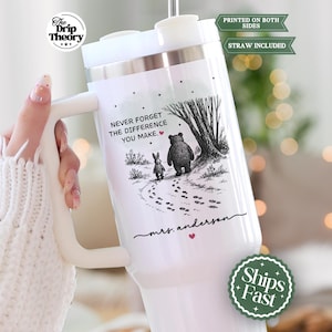 May include: White insulated tumbler with a handle, featuring a black and white illustration of a bear and rabbit walking on a path. Text reads "Never forget the difference you make." Includes a straw.