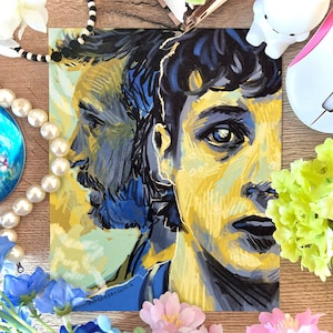 Könnte beinhalten: Ein farbenfroher Porträtdruck mit zwei Gesichtern im Profil, dargestellt in Gelb, Blau und Schwarz. Das Kunstwerk hat einen malerischen Stil mit sichtbaren Pinselstrichen. Der Druck ist von dekorativen Elementen wie Blumen und Schmuck umgeben.