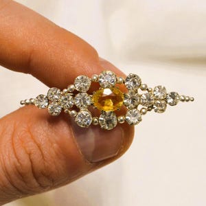 Broche vintage estilo boho revival vitoriano com citrino de vidro e strass transparentes, em tom prateado, década de 1950.