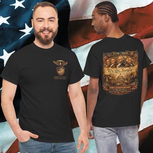 May include: Black t-shirts with patriotic designs. One shirt features an eagle and shield emblem with the text "Liberty & Unity". The other shirt displays the text "We The People" with an image of historical figures and the Capitol building.