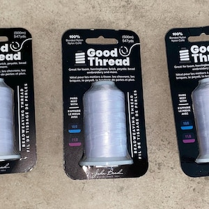 May include: Three spools of white Good Thread bonded nylon beadweaving thread on black retail cards. Each card displays the brand name, 100% bonded nylon, 547 yards, and 500 meters. The packaging indicates compatibility with loom, brick, and peyote stitch.