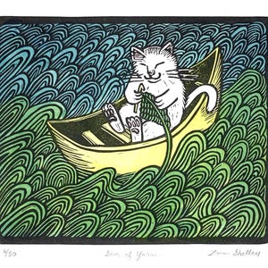 May include: A whimsical art print depicts a white cat knitting in a yellow boat, surrounded by green and blue waves. The image is titled "Son of Yarn" and signed by the artist. The print has a black border.