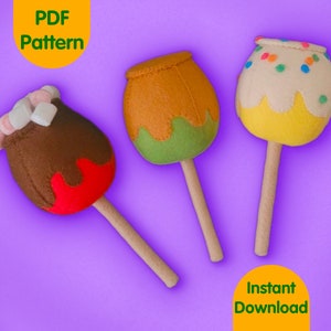 May include: Three felt candy apple ornaments on sticks. The apples are decorated with chocolate, sprinkles, and green and yellow felt. The sticks are wooden.