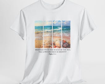 Puede incluir: Camiseta blanca con una escena de playa, que muestra olas del océano, arena y conchas marinas. El texto en la camiseta dice: "MIGHTIER THAN THE WAVES OF THE SEA, THE LORD ON HIGH IS MIGHTY! Salmos 93:4."
