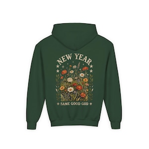 May include: A dark green hoodie with a floral design and the text "NEW YEAR" above and "* SAME GOOD GOD *" below. The floral design includes various flowers in shades of white, orange, and yellow.