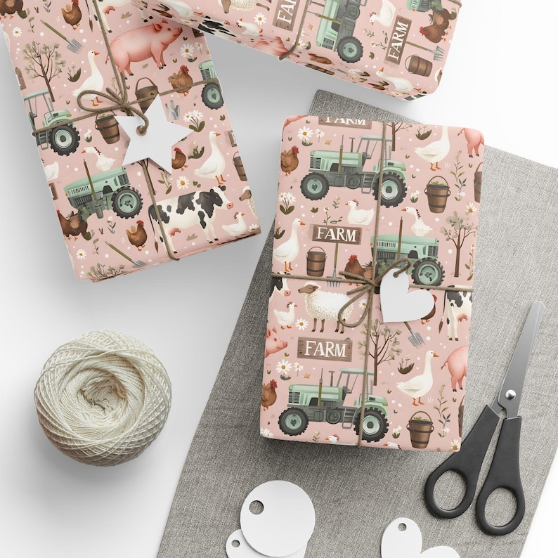 May include: Pink wrapping paper with a farm theme. The paper features illustrations of farm animals, tractors, and other farm-related objects. The paper is decorated with white twine and a white tag that says 'Farm'.