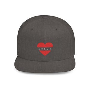 Könnte beinhalten: Eine dunkelgraue Baseballkappe mit flachem Schirm, einem roten Herzen und dem Wort "JESUS" in weißen Buchstaben.