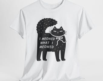May include: White t-shirt featuring a black cat illustration with a fluffy tail and a bow tie. The text "I meowed what I meowed" is printed below the cat. A casual, comfortable tee for cat lovers.