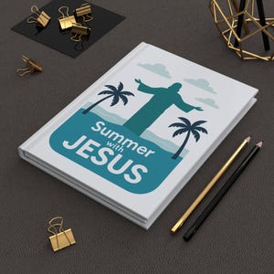Könnte beinhalten: Ein weißes Notizbuch mit dem Text "Summer with Jesus" in Türkis. Das Cover zeigt eine türkisfarbene Grafik von Jesus mit Palmen und Wolken. Goldene und schwarze Bleistifte und goldene Büroklammern befinden sich in der Nähe.