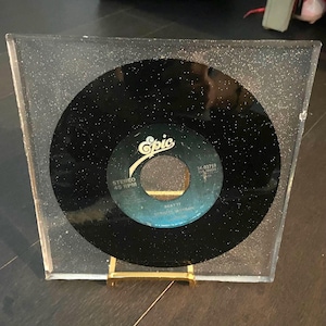 Peut inclure: Un disque vinyle noir avec un cadre argenté à paillettes. L'étiquette du disque est noire avec du texte blanc et un logo Epic rouge et blanc. Le texte sur l'étiquette indique "Beat It" de Michael Jackson, "Stéréo 45 RPM" et "34-03759".