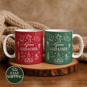 May include: Two ceramic mugs, one red and one green, each featuring white line art of a church, cross, bible, wings, and praying hands. The text reads Grace's GODFATHER and 2026. Both mugs have a white interior and a white handle on the side.