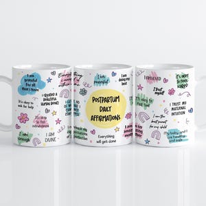 May include: Three white ceramic mugs featuring colorful hand-lettered affirmations and doodles. The central mug displays the text Postpartum Daily Affirmations in a yellow circle, surrounded by phrases like I am enough and I trust my maternal intuition.