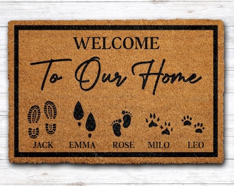 May include: A rectangular doormat with a black border and the words "WELCOME To Our Home" in black script. The mat features footprints, paw prints, and names: Jack, Emma, Rose, Milo, and Leo.