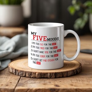 May include: A white ceramic mug featuring the black text MY FIVE MOODS followed by a numbered list of five statements ending in the word SHIT highlighted in red boxes. The text includes: 1. I'm too OLD FOR THIS SHIT, 2. I'm too TIRED FOR THIS SHIT, 3. I DON'T HAVE TIME FOR THIS SHIT, 4. I'm too SOBER FOR THIS SHIT, 5. I DON'T GET PAID ENOUGH FOR THIS SHIT.