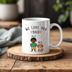 May include: A white ceramic mug featuring the black text "WE LOVE YOU DAD" with two small red hearts. Below, a cartoon illustration shows a boy labeled "JACK" in a green shirt and yellow shorts next to a brown dog labeled "MAX" with gold stars.