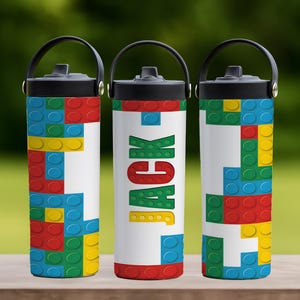 May include: Three insulated water bottles with black handles and lids. The bottles are white with a colorful design of toy building blocks in red, blue, green, and yellow. The center bottle has the name "JACK" in colorful letters.