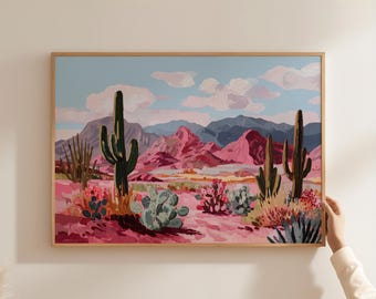 May include: A framed painting of a desert landscape, featuring cacti, mountains, and a blue sky with clouds. The artwork uses pinks, greens, and blues to create a vibrant desert scene. The frame is made of light-coloured wood, adding to the artwork's aesthetic.