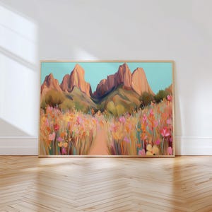 May include: A framed landscape painting depicts a desert scene with mountains and wildflowers. The artwork features a path leading towards the mountains, with a color palette of pinks, oranges, and greens. The sky is a light blue.