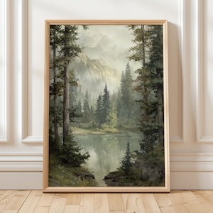 Puede incluir: Una pintura de paisaje enmarcada representa una serena escena forestal. Altos árboles de hoja perenne rodean un lago tranquilo, con montañas al fondo. La obra de arte está realizada en tonos verdes, azules y marrones apagados, creando una atmósfera tranquila. El marco es de madera clara.