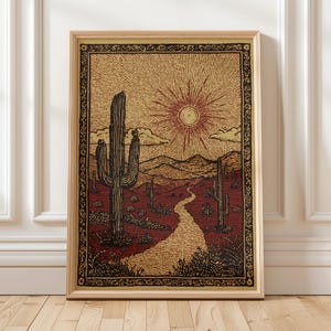 May include: Framed art print depicting a desert scene with a cactus, a path, and a sun. The artwork uses red, tan, and black tones, with a detailed border. The print is presented in a natural wood frame, suitable for wall display.