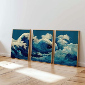 Puede incluir: Tres impresiones artísticas enmarcadas que representan olas oceánicas estilizadas. La obra de arte utiliza tonos de azul y blanco sobre un fondo azul oscuro. Los marcos son de color marrón claro y las impresiones se exhiben sobre un suelo de madera.