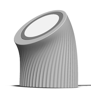 May include: A modern, gray wireless charging station with a curved, ridged design. The top surface is angled and features a white charging area with a gray border. The base has vertical, wave-like grooves.