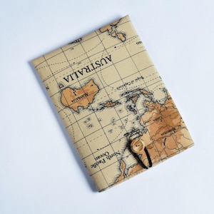 May include: A beige fabric journal cover with a world map design. The cover features a button closure and a map of Australia. The journal is rectangular and has a vintage aesthetic.