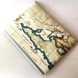 May include: A beige fabric pouch with a map design featuring the Arctic Ocean, Laptev Sea, East Siberian Sea, Bering Sea, and the North Pacific Ocean. The pouch has a silver zipper.